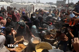 Người dân Palestine nhận thực phẩm cứu trợ tại Gaza. (Ảnh: THX/TTXVN)
