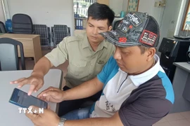 Nhân viên Văn phòng kiểm tra, kiểm soát nghề cá cảng Cát Lở, phường Phước Thắng, Thành phố Hồ Chí Minh hướng dẫn chủ tàu cá làm thủ tục xuất bến điện tử 2. (Ảnh: Hoàng Nhị - TTXVN)
