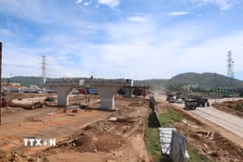 Công nhân thi công trên cầu vượt trong khi phía dưới, dòng phương tiện vẫn lưu thông liên tục trên Quốc lộ 14B. (Ảnh: Xuân Quý/TTXVN)