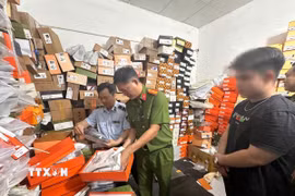 Công an thành phố Cần Thơ phối hợp Chi Cục quản lý thị trường thành phố kiểm đếm số quần áo “giả” thương hiệu nổi tiếng tại cửa hàng T.H Luxury. (Ảnh: TTXVN phát)