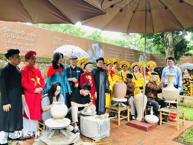Collection author, artisan and collector Nguyen Duc Cong takes souvenir photos with delegates and people of Bat Trang craft village. (Photo: Tuyet Mai/VNA) ttxvn-gom-bat-trang-2.jpg