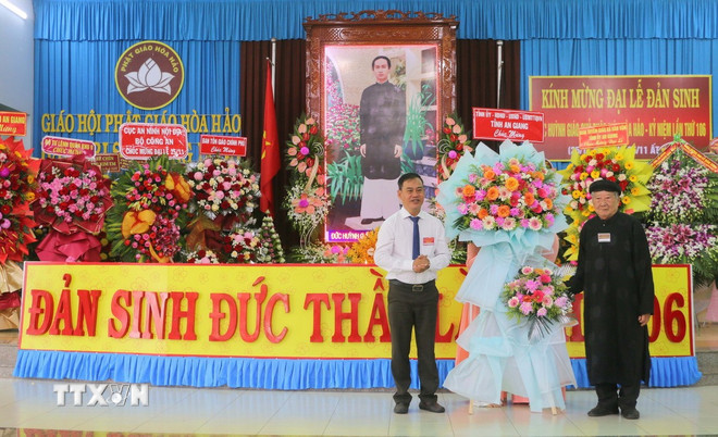 Ông Danh Phúc, Giám đốc Sở Dân tộc và Tôn giáo tỉnh An Giang (trái) thay mặt Tỉnh ủy, Hội đồng nhân dân, Ủy ban nhân dân, Ủy ban Mặt trận Tổ quốc Việt Nam tỉnh An Giang tặng hoa, chúc mừng lễ kỷ niệm 106 năm Ngày Đản sinh Đức Huỳnh Giáo chủ Phật giáo Hòa Hảo. (Ảnh: Công Mạo/TTXVN)