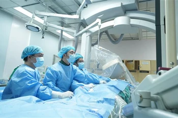 Các bác sỹ Bệnh viện Đại học Y dược thực hiện phẫu thuật thay van động mạch phổi qua da cho người bệnh. (Ảnh: TTXVN phát)