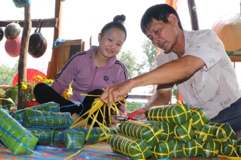 Không khí sum vầy của ngày Tết trong dịp gói bánh tét. (Ảnh: Nguyễn Hằng/TTXVN)