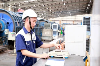 Kỹ sư Nguyễn Văn Tuân kiểm tra tỷ trọng cáp điện, một trong những hoạt động của nghiên cứu để giảm tỷ trọng lõi dẫn, giảm giá thành sản xuất cáp điện. (Ảnh: Minh Thu/TTXVN)