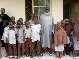 Cụ ông Barinjimi (giữa) chụp ảnh với "các bạn" cùng lớp. (Ảnh: AFP/TTXVN) 