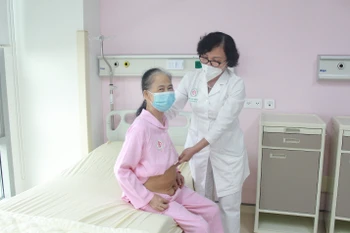 Bác sỹ Nguyễn Thanh Hà thăm khám cho bệnh nhân sau phẫu thuật. (Ảnh: PV/Vietnam+)