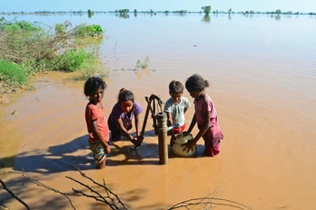 Trẻ em lấy nước sinh hoạt tại khu vực ngập lụt ở Jalandhar, bang Punjab (Ấn Độ). (Ảnh: AFP/TTXVN)