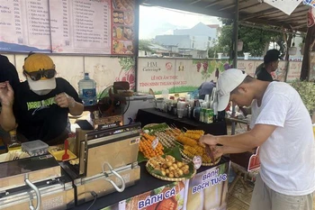 Du khách tìm hiểu các món ăn được bày bán tại lễ hội. (Ảnh: Công Thử/TTXVN)