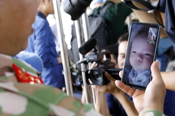 Cuộc điện thoại chào tạm biệt con nhỏ 4 tháng tuổi của một chiến sỹ công binh trước giờ lên đường làm nhiệm vụ. (Ảnh: An Đăng/TTXVN)