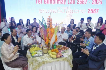 Các đại biểu thực hiện nghi lễ theo phong tục Tết Bunpimay của Lào. (Ảnh: Thu Hằng/TTXVN)