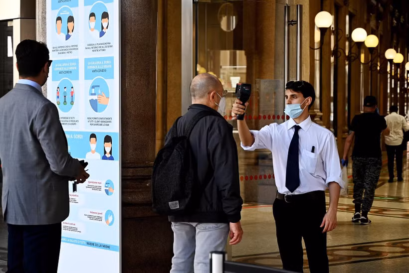 Kiểm tra thân nhiệt phòng lây nhiễm COVID-19 trước khi vào một trung tâm mua sắm ở Rome, Italy. (Ảnh: AFP/TTXVN)