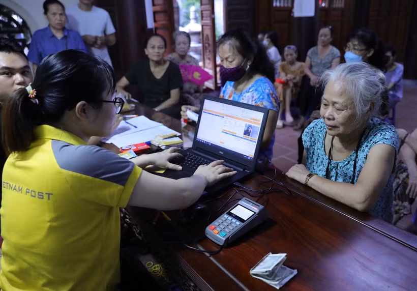 Kiểm tra thông tin của người đến nhận chi trả bảo hiểm, trợ cấp. (Ảnh: Hoàng Hiếu/TTXVN)