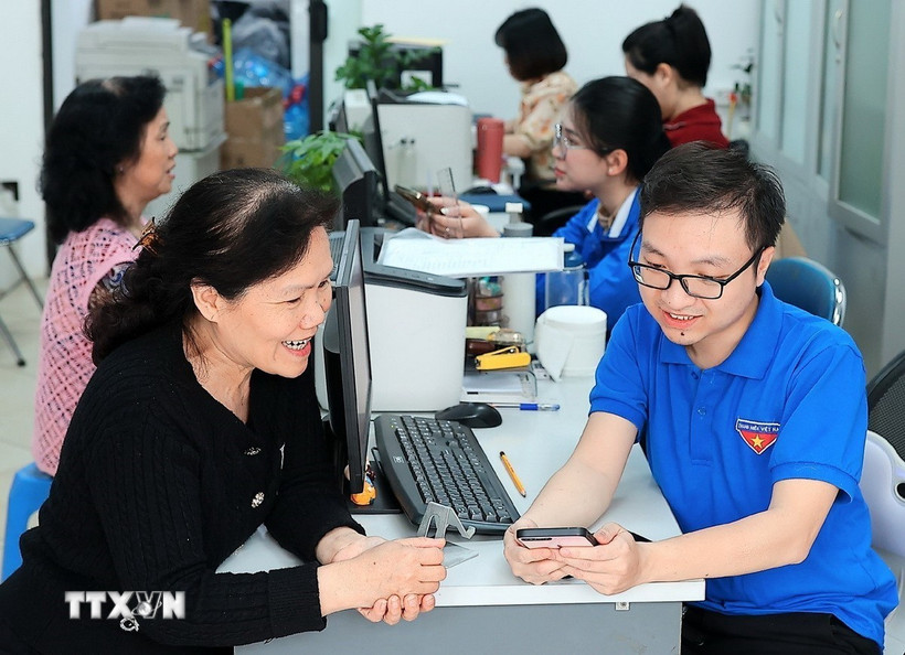 Đoàn viên thanh niên phường Hàng Bồ (quận Hoàn Kiếm, thành phố Hà Nội) hỗ trợ người dân thực hiện thủ tục hành chính công trên thiết bị điện thoại thông minh. (Ảnh: Phạm Hậu/TTXVN)