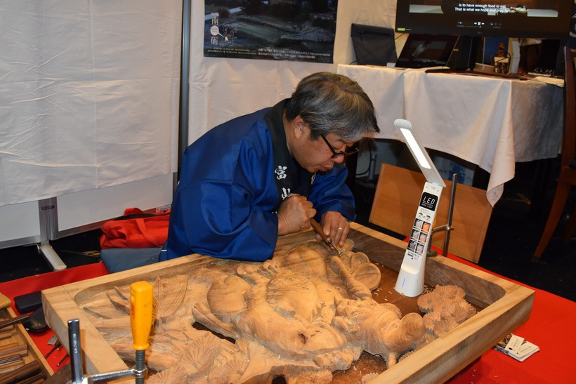 Nghệ nhân Sakai Hidetoshi đang chạm khắc bức phù điêu ba chiều tượng Ebisu. (Ảnh: Nguyễn Tuyến/Vietnam+)