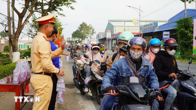 Những chai nước uống, những cái vẫy tay chào, những nụ cười… từ các tình nguyện viên của “Trạm dừng chân nghĩa tình” khiến nhiều người đi đường cảm thấy ấm lòng trên đường về quê. (Ảnh: Nhựt An/TTXVN)