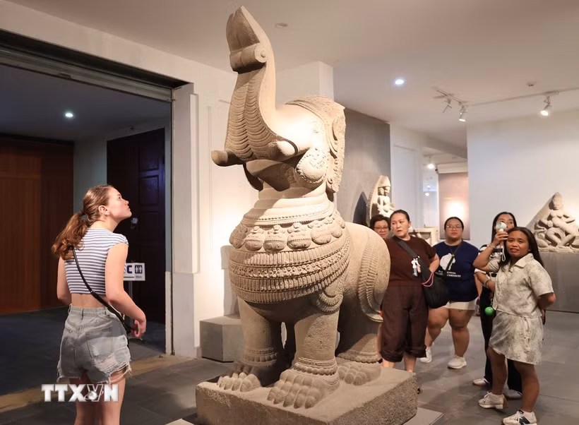Du khách nước ngoài tìm hiểu về hiện vật trưng bày tại Bảo tàng Điêu khắc Chăm Đà Nẵng. (Ảnh: Kha Phạm/TTXVN)