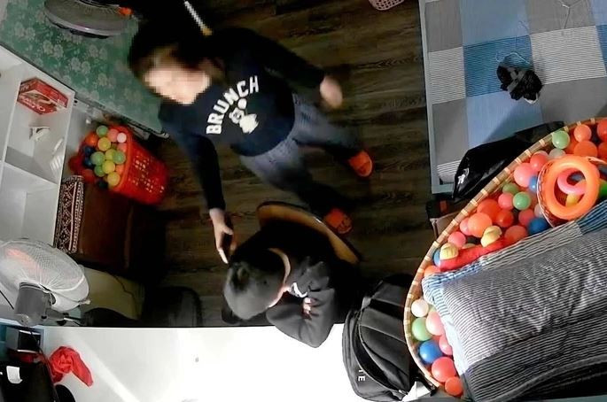 Hình ảnh video thể hiện cảnh được cho là bé trai bị mẹ kế cầm điện thoại đánh vào đầu. (Nguồn: Ảnh cắt từ clip)