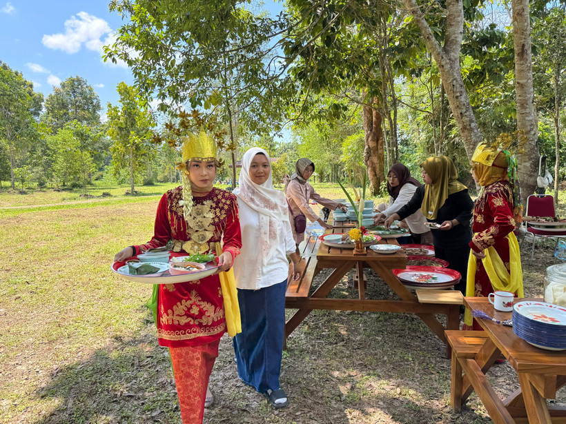 Các cô gái mời những vị khách đặc biệt sản vật địa phương trong bữa trưa ngay dưới tán cây trong Khu đền cổ. (Ảnh: Đỗ Quyên/TTXVN)