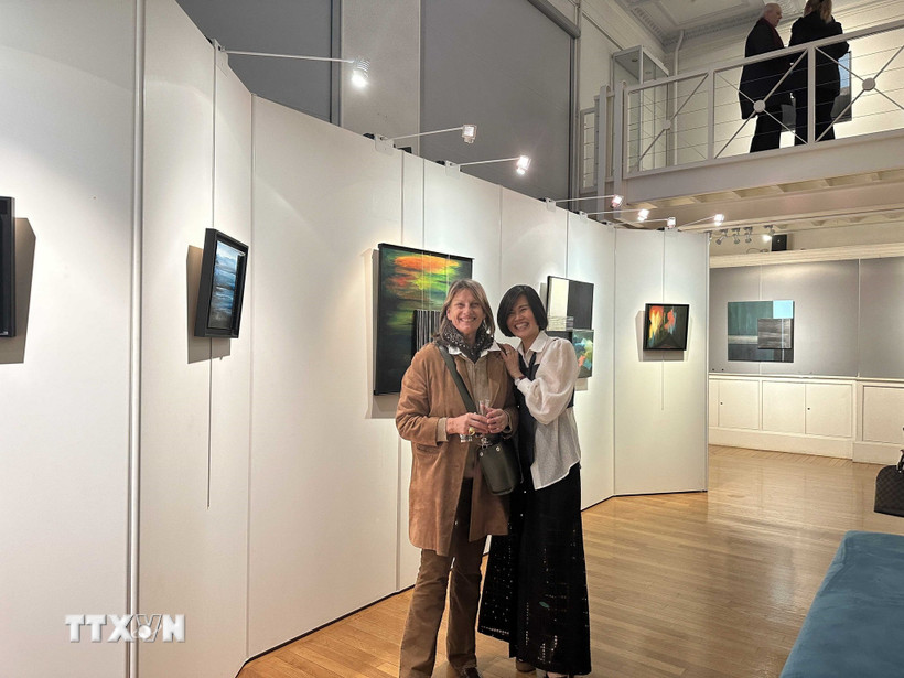 Họa sỹ Liên Phạm (bên phải) chia sẻ cảm xúc vui mừng với bạn bè Pháp tại Triển lãm. (Ảnh: Ngọc Hiệp/TTXVN)