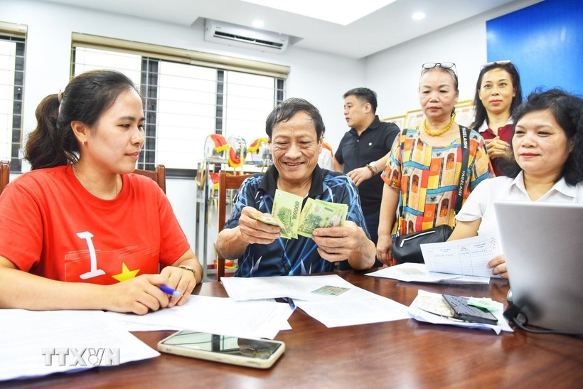 Người dân đến đăng ký nhận quà tại điểm chi trả phường Bồ Đề (Hà Nội). (Ảnh: Minh Quyết/TTXVN)