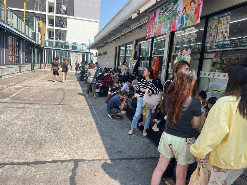 Người dân trú tạm dưới bóng râm của cửa hàng tiện lợi chờ đến khi được phép trở lại nhà. (Ảnh: Huy Tiến/TTXVN)