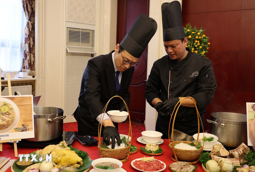 Quan chức ngoại giao tại Trung Quốc trải nghiệm cách chế biến một tô phở. (Ảnh: Hải Yến/TTXVN)