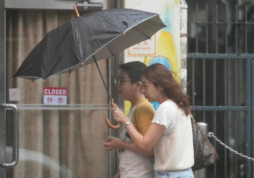 Người dân di chuyển trên đường phố trong gió lớn do ảnh hưởng của bão Wipha tại Trung Quốc. (Ảnh: THX/TTXVN)