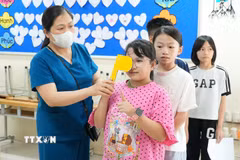 Kiểm tra thị lực cho trẻ em trong chương trình khám khám sàng lọc miễn phí. (Ảnh: TTXVN)