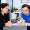 Đoàn viên thanh niên phường Hàng Bồ (quận Hoàn Kiếm, thành phố Hà Nội) hỗ trợ người dân thực hiện thủ tục hành chính công trên thiết bị điện thoại thông minh. (Ảnh: Phạm Hậu/TTXVN)