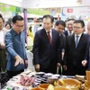 Lãnh đạo thương mại Việt Nam, Lào và các đại biểu tham quan gian hàng của Việt Nam tại Hội chợ. (Ảnh: Xuân Tú/TTXVN)