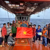 Lực lượng chấp pháp trên biển trao cờ tổ quốc và tuyên truyền IUU cho ngư dân đang đánh bắt trên biển. (Ảnh: Hoàng Nhị/TTXVN)