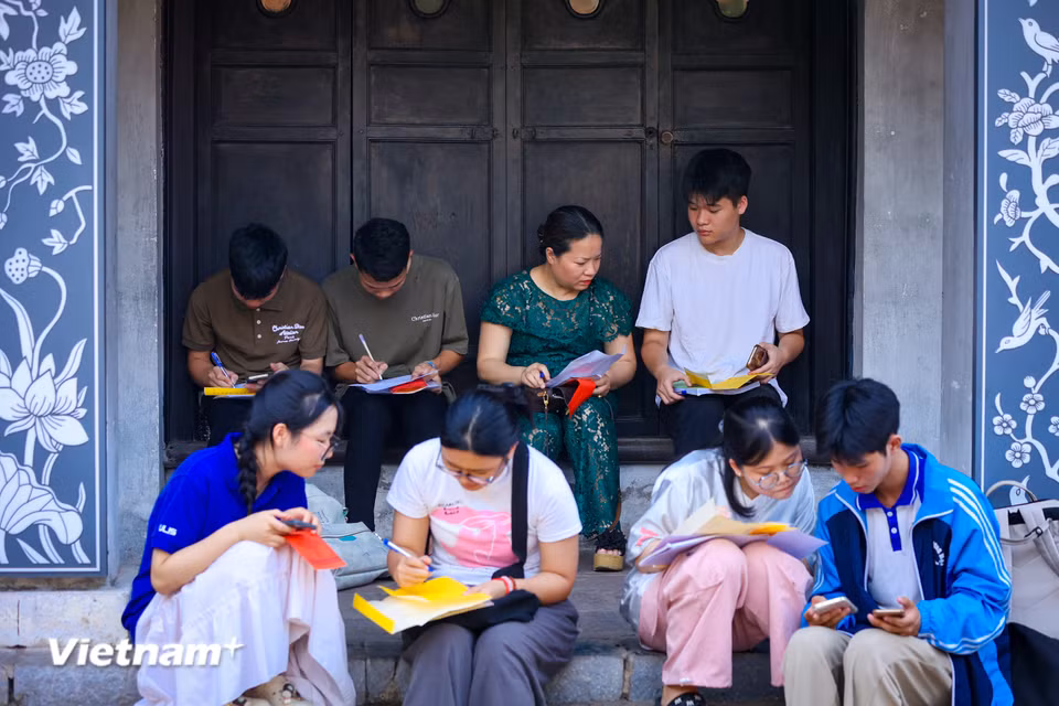 Các sĩ tử tự tay ghi sớ thông tin cá nhân để chuẩn bị khấn mong cho sự may mắn, thuận lợi trong kỳ thi tốt nghiệp. (Ảnh: Hoài Nam/Vietnam+)