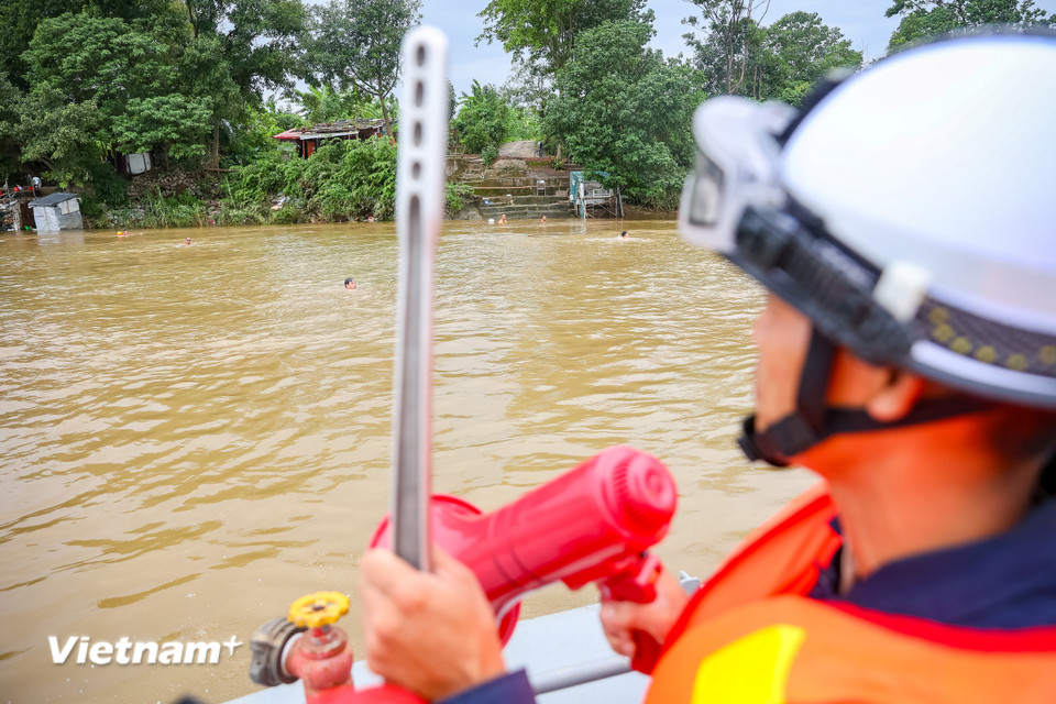 Lực lượng chức năng vận động người dân dừng việc bơi lội trên sông Hồng vào thời điểm bão sắp ảnh hưởng tới đất liền. (Ảnh: Hoài Nam/Vietnam+)