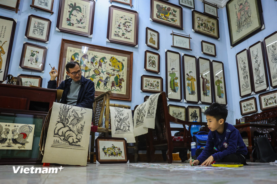 Ở gia đình 'tam đại đồng đường' cũng là cả 3 thế hệ gắn gó với nghề làm tranh dân gian truyền thống, Nguyễn Hữu Minh Đăng năm nay lên 7 cũng đã 'chập chững' quan tâm về nghề của bố và ông nội mình. (Ảnh: Hoài Nam/Vietnam+)
