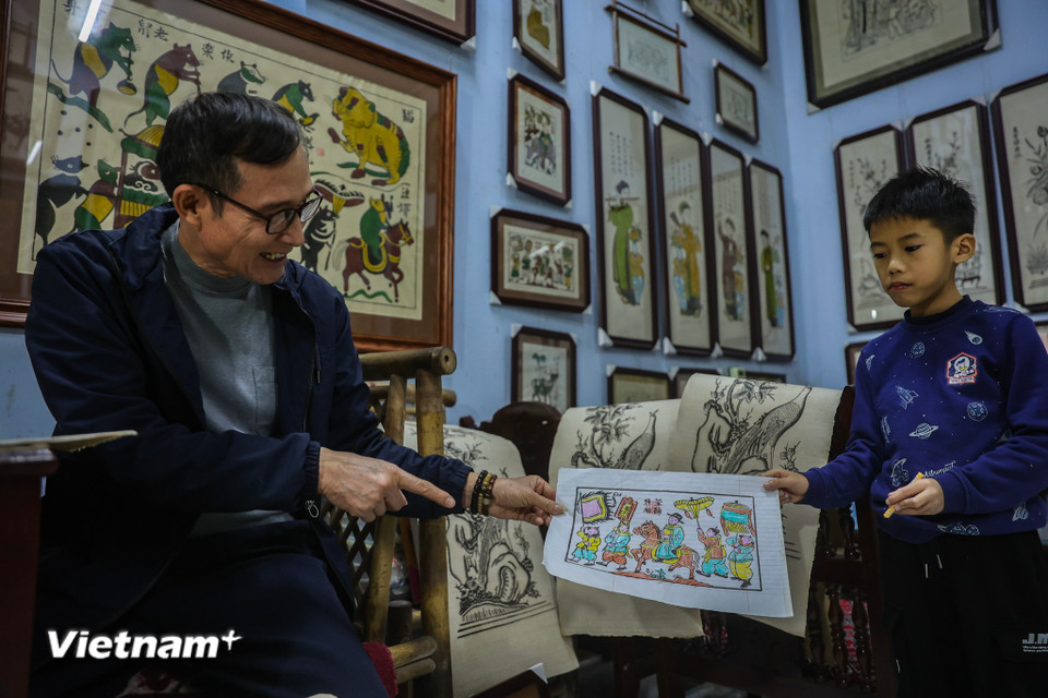 Nghệ nhân Quả tự hào, thấy niềm tin về nghề mang đậm văn hóa truyền thống vẫn âm ỉ chảy trong gia đình mình, ông thấy cả hình ảnh của mình và cậu con trai hồi nhỏ khi thấy cháu sau giờ học lại quấn quít bên tranh. (Ảnh: Hoài Nam/Vietnam+)