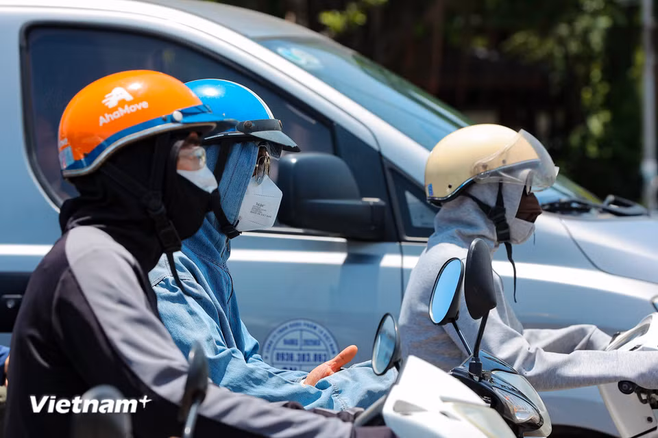 Người dân ra đường với trang phục kín mít để chống chọi lại cái nắng gắt đầu mùa. (Ảnh: Hoài Nam/Vietnam+)