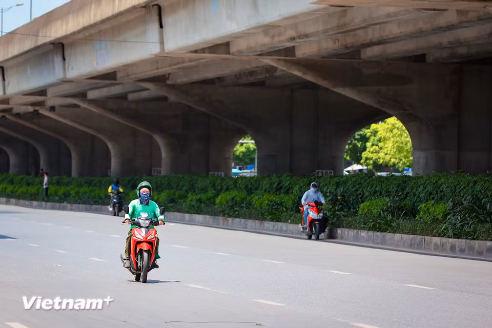 Vào thời điểm giữa trưa nắng, đường vành đai 3 vắng người qua lại, xe máy tận dụng bóng râm ít ỏi để tránh nắng. (Ảnh: Hoài Nam/Vietnam+)