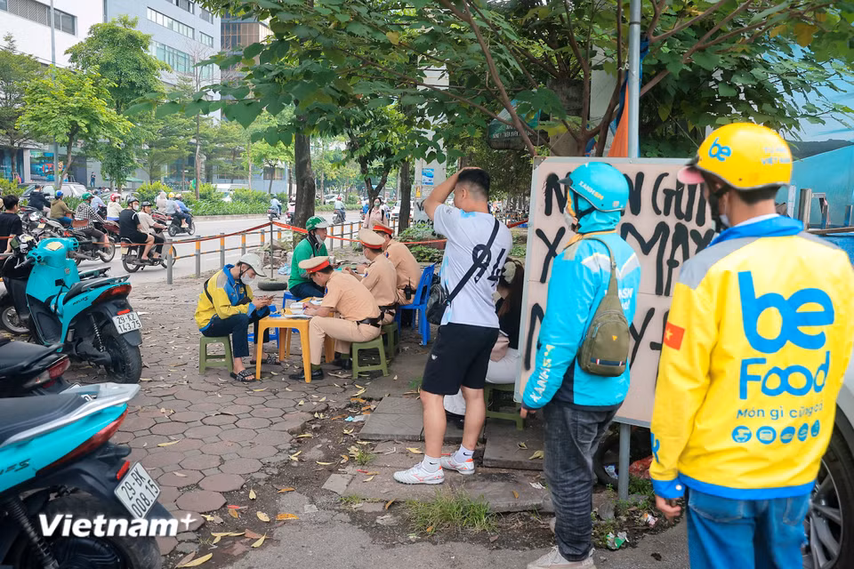Tài xế xe ôm công nghệ xếp hàng nhận biên bản xử lý vi phạm tại tổ công tác khu vực đường Phạm Hùng (Nam Từ Liêm, Hà Nội). (Ảnh: Hoài Nam/Vietnam+)