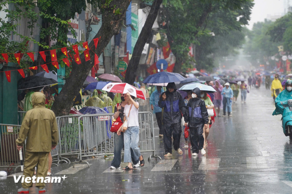 Người dân ùn ùn trở về khu vực Kim Mã trong thời tiết mưa lớn. (Ảnh: Hoài Nam/Vietnam+)