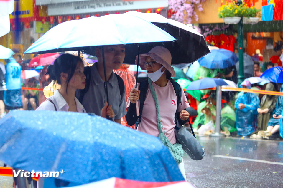 Đến thời điểm 15 giờ 20, trời vẫn mưa nặng hạt nhưng dòng người vẫn đổ về các khu vực gần quảng trường Ba Đình. (Ảnh: Hoài Nam/Vietnam+)