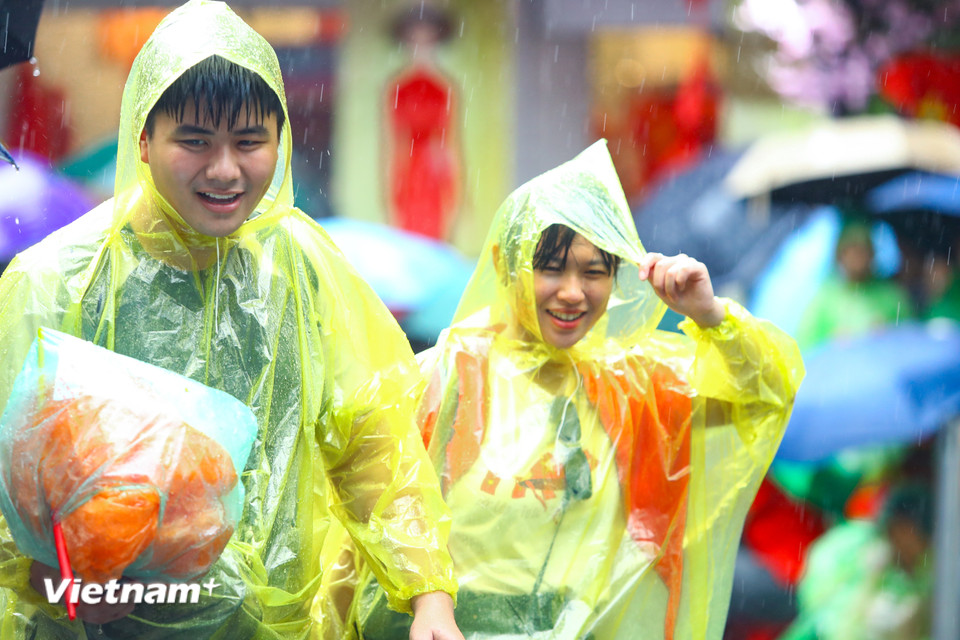 Chiều 1/9, thời tiết Hà Nội có những cơn mưa rào bất chợt nhưng người dân vẫn 'đội mưa' trở về các tuyến phố nơi có đoàn diễu binh, diễu hành đi qua để xếp hàng chờ xem Đại lễ kỷ niệm 80 năm Quốc khánh 2/9. (Ảnh: Hoài Nam/Vietnam+)