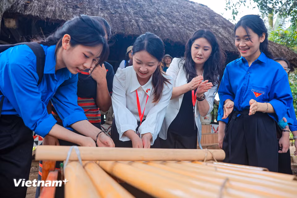 Thanh niên Việt Nam cùng Đoàn thanh niên Trung Quốc cùng nhau trải nghiệm sử dụng đàn K'lông pút. (Ảnh: Hoài Nam/Vietnam+)
