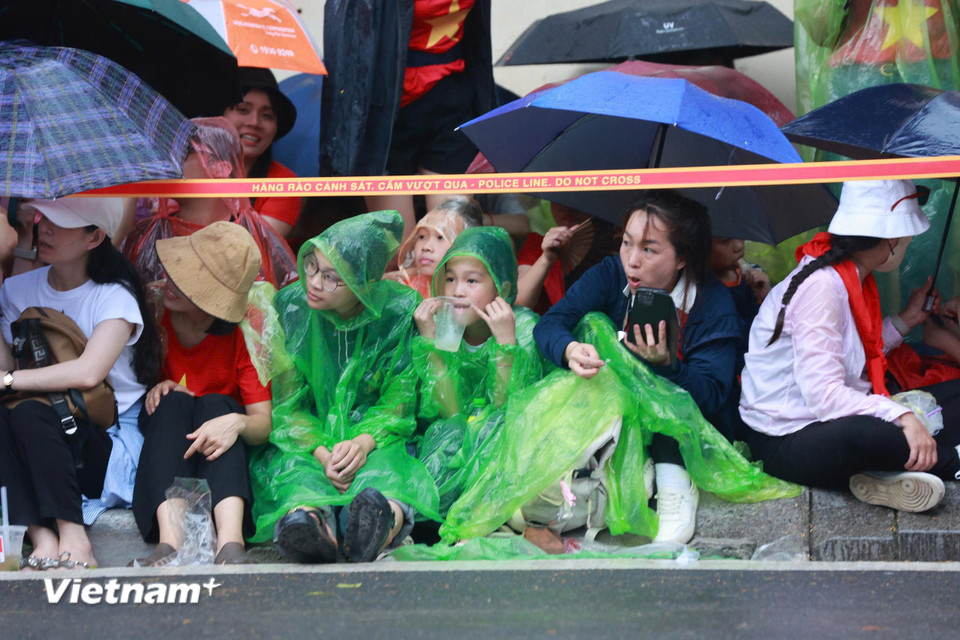 Người dân đội mưa đón chờ màn diễu binh, diễu hành. (Ảnh: Hoài Nam/Vietnam+)