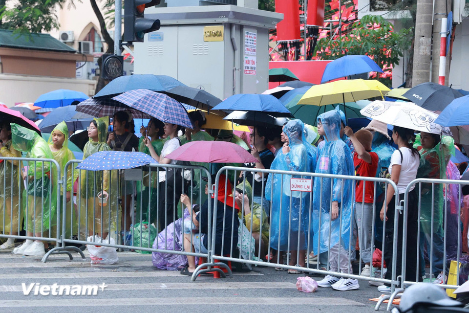 Người dân đội mưa chờ đợi tại khu vực Hàng Cháo-Nguyễn Thái Học. (Ảnh: Hoài Nam/Vietnam+)