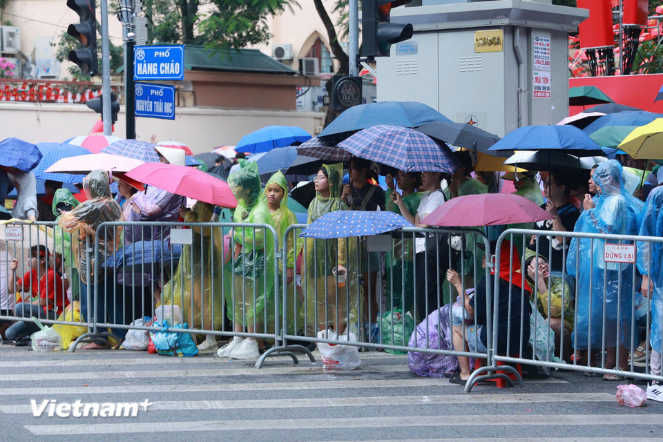 Đến khoảng 13 giờ 30 trời bắt đầu đổ mưa nhưng người dân vẫn kiên trì chờ đợi tại khu vực Hàng Cháo-Nguyễn Thái Học. (Ảnh: Hoài Nam/Vietnam+)