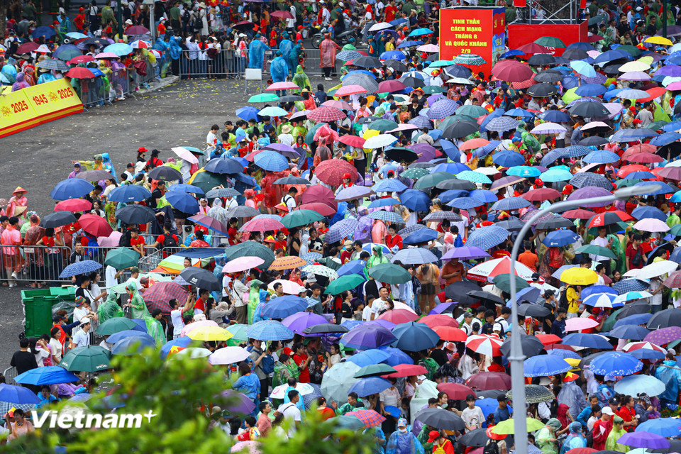 Người dân đội mưa đón chờ màn diễu binh, diễu hành. (Ảnh: Hoài Nam/Vietnam+)