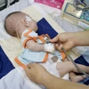Bác sỹ khám, theo dõi sức khỏe cho một trẻ mắc sởi. (Ảnh: TTXVN/Vietnam+)