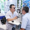 Bác sỹ kiểm tra mắt cho người cao tuổi tại buổi lễ phát động. (Ảnh: PV/Vietnam+)