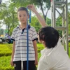 Nhân viên y tế đo chiều cao cho trẻ tại ngày hội. (Ảnh: PV/Vietnam+)